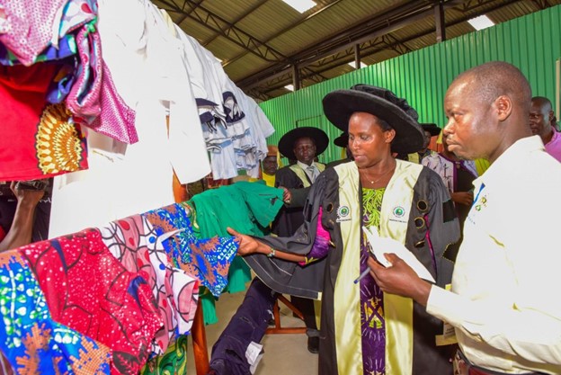 The State House Comptroller Jane Barekye (second right) with guidance of Head of Tailoring Department Robert Okabo (right) admire some of the cloths done by the students during the 1st graduation of the Presidential Initiative for Zonal Industrial Parks for Skills Development, Value Addition and Wealth creation at the Acholi Zonal Industrial Hub in Gulu district, Aswa County, Unyama Sub-county, Oding Village on 3rd January 2023