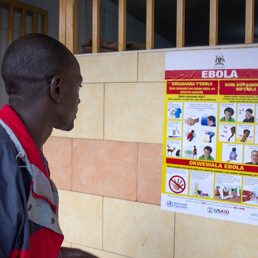 A Ugandan reading a poster on how Ebola spreads